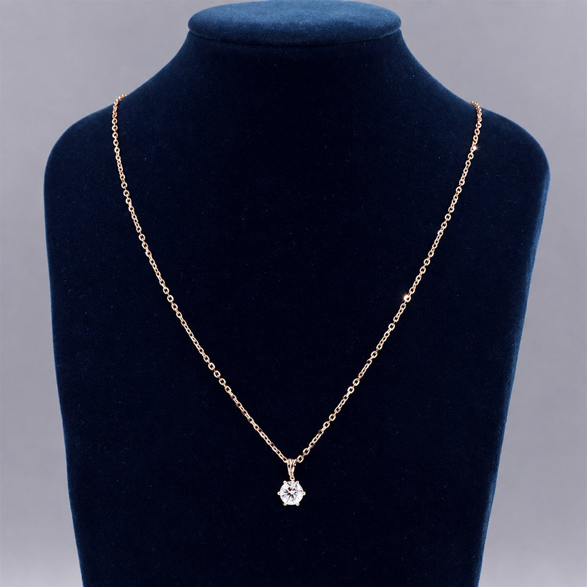 Rose gold moissanite necklace on a black necklace display