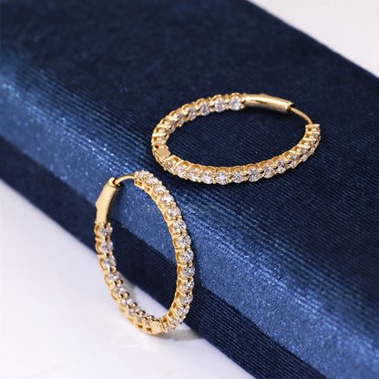 Yellow gold diamond hoops on dark fabric