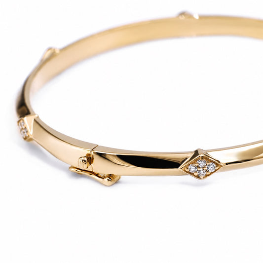 Close view of a lozenge-shaped lab diamond accent on the gold bangle
