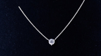 White gold solitaire moissanite necklace on a black display