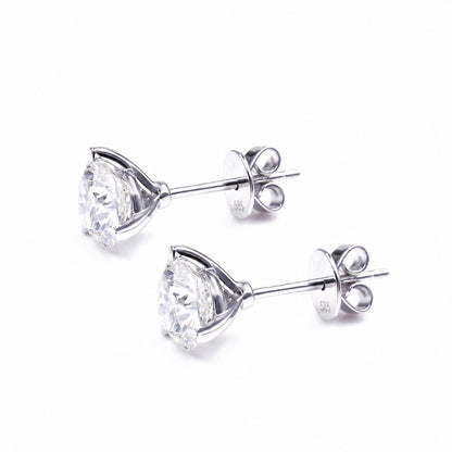 Three-claw moissanite studs in a pale metal tone, side view