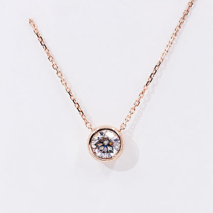 Round moissanite in a rose gold bezel on white