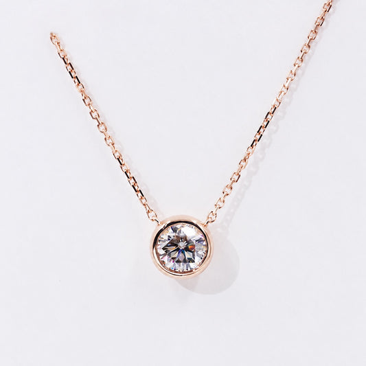 Round moissanite in a rose gold bezel on white